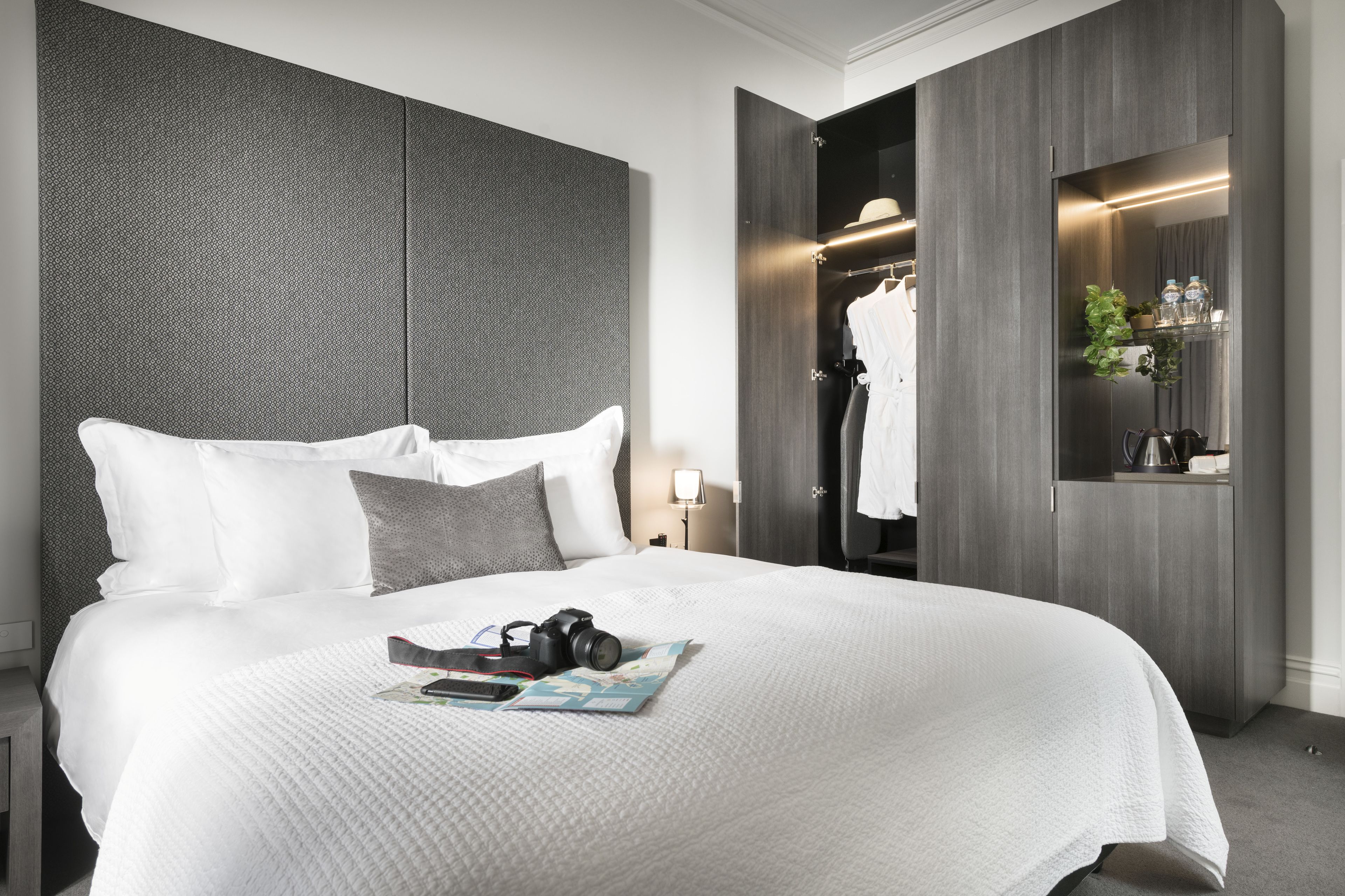 Une chambre d’hôtel moderne avec un grand lit, une armoire et un miroir.