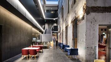 A modern interior with a central staircase, tables, and chairs arranged for dining.