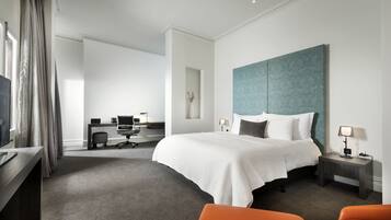 Una habitación de hotel moderna con una cama grande, un escritorio con computadora, una silla y un televisor.