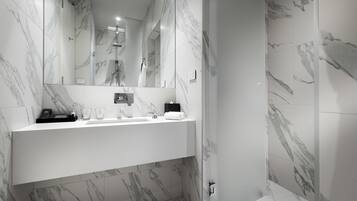 A modern bathroom with marble walls, a white vanity, and a large mirror.