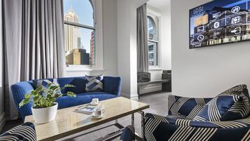 Una sala de estar moderna con un sofá azul, una mesa de centro de madera y una planta en maceta.
