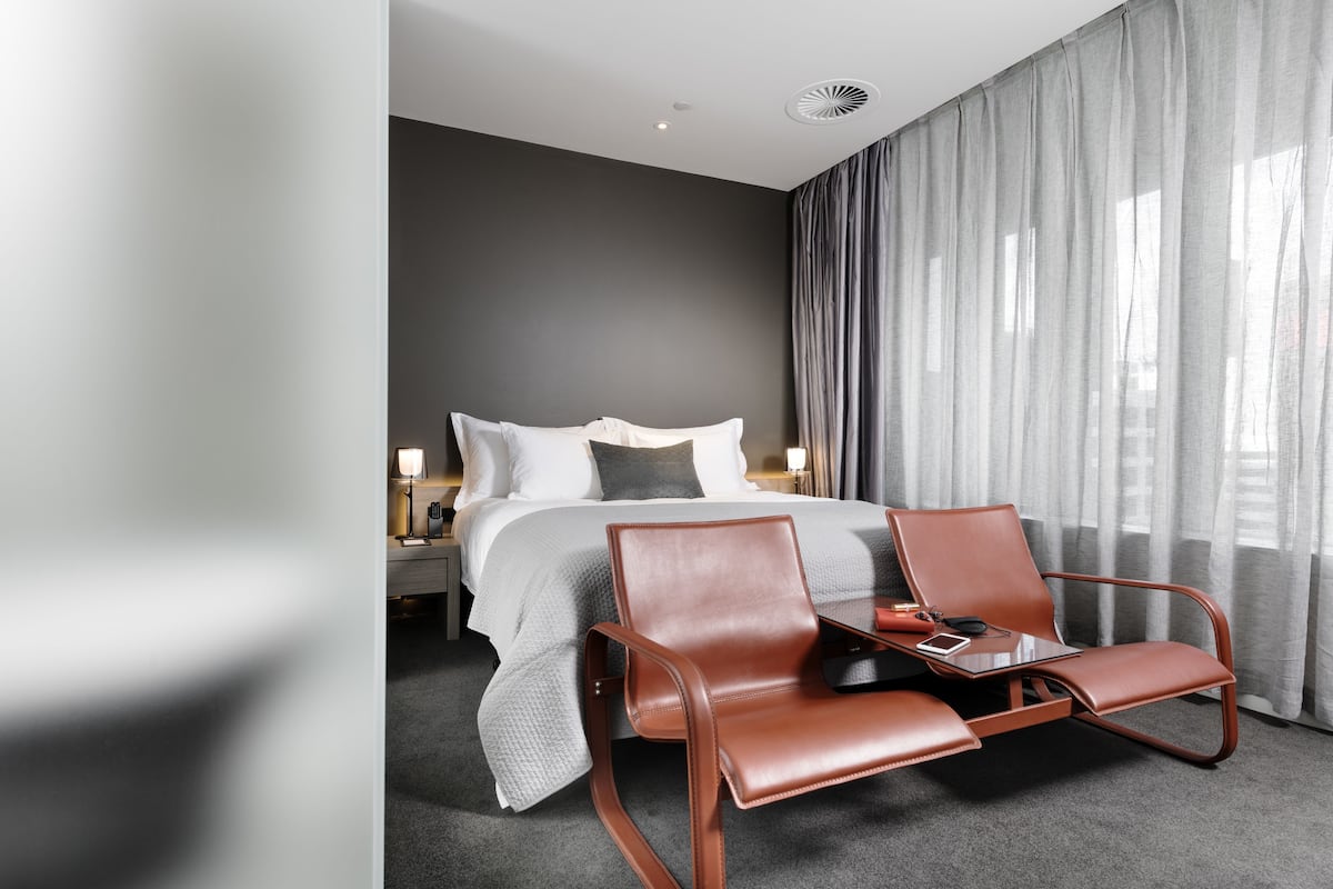 A modern hotel room with a bed, a desk, and a chair.
