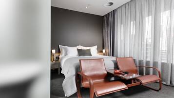 A modern hotel room with a bed, a desk, and a chair.