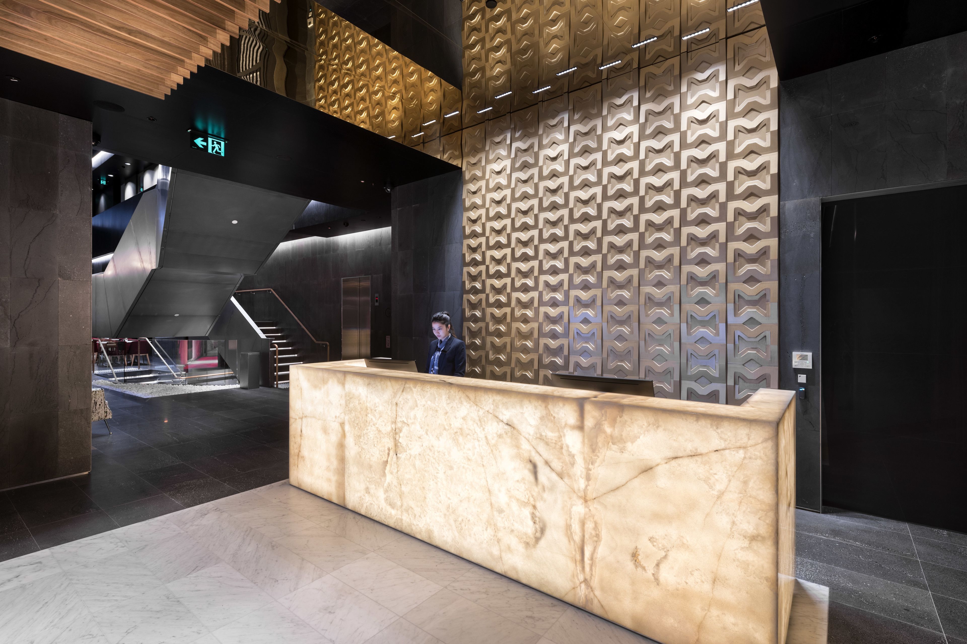A reception area with a marble counter, a staircase, and a patterned wall.