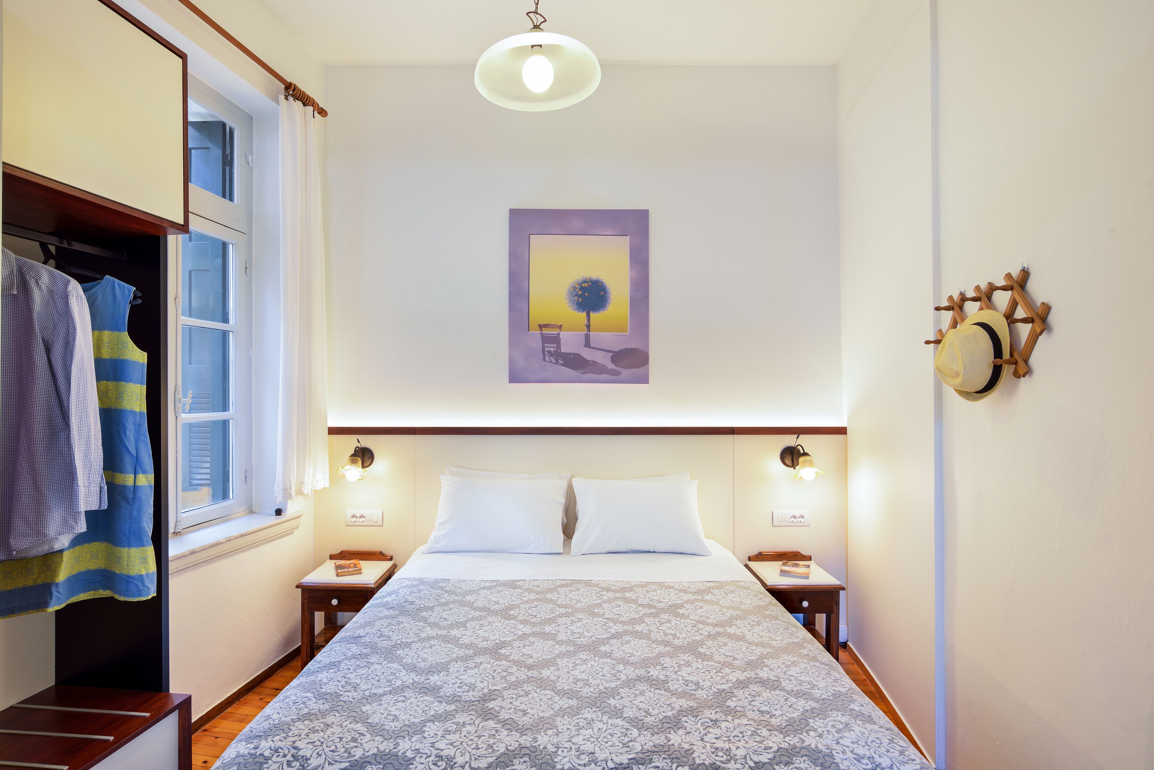 A neatly arranged bedroom with a bed, bedside tables, a wardrobe, and a window with curtains.