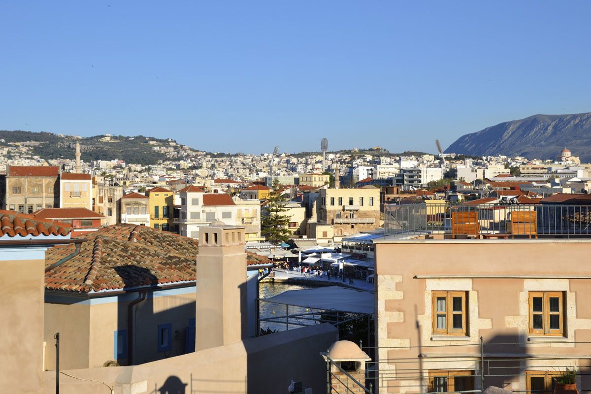 Un paisaje urbano con edificios residenciales y comerciales, una estructura cúpula destacada y un telón de fondo montañoso.