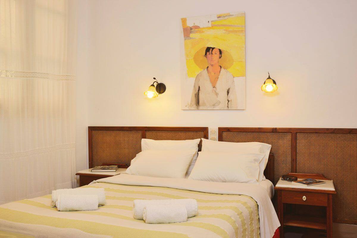 Quarto de hotel com uma cama, duas mesas de cabeceira, um quadro na parede e duas luminárias.