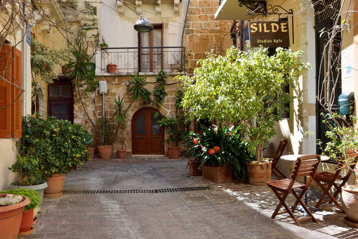 Un patio con plantas en macetas, una puerta de madera y un letrero que dice 'Silde Studios Apts'.