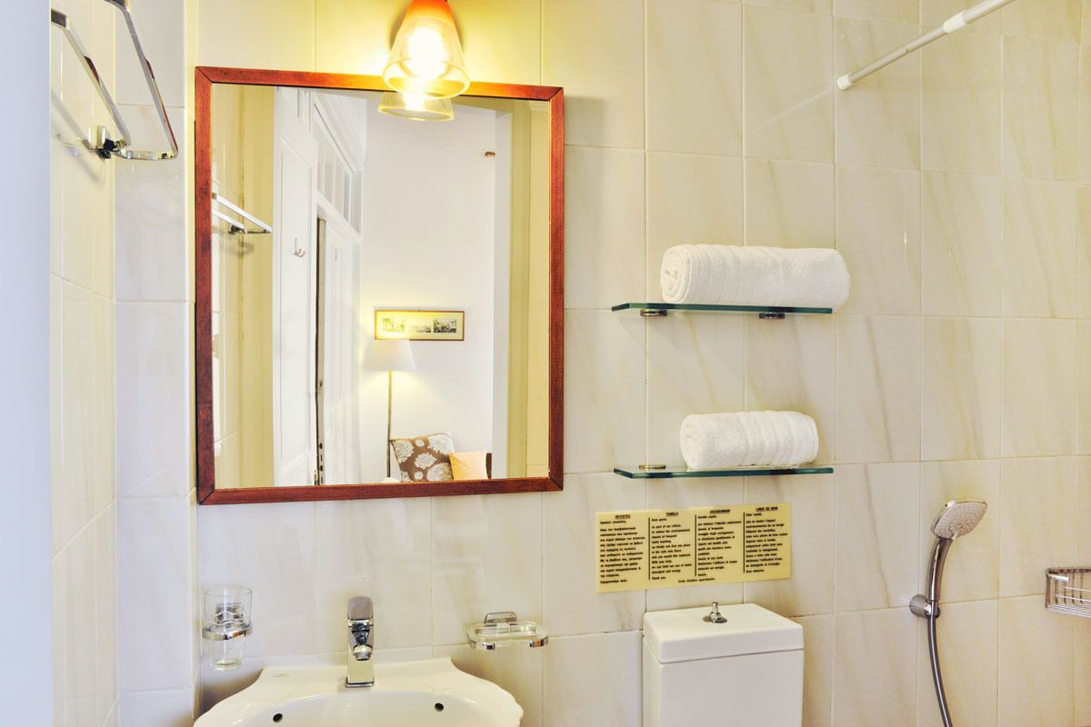 A bathroom with a sink, mirror, towel rack, and a shower.