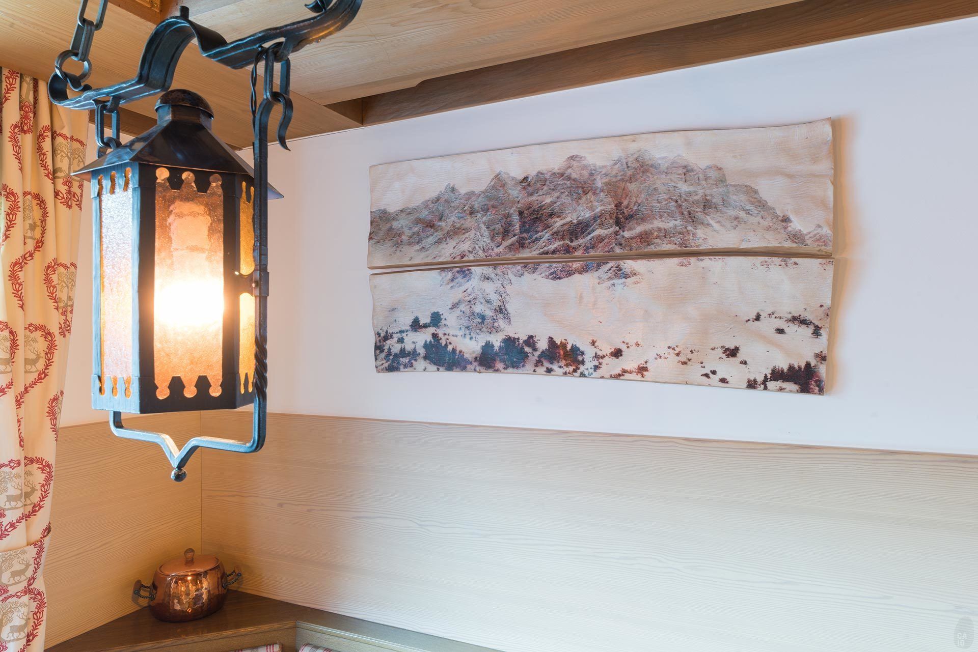Una habitación con techo de madera rústica, un farol colgante de metal y un cuadro abstracto grande en la pared.