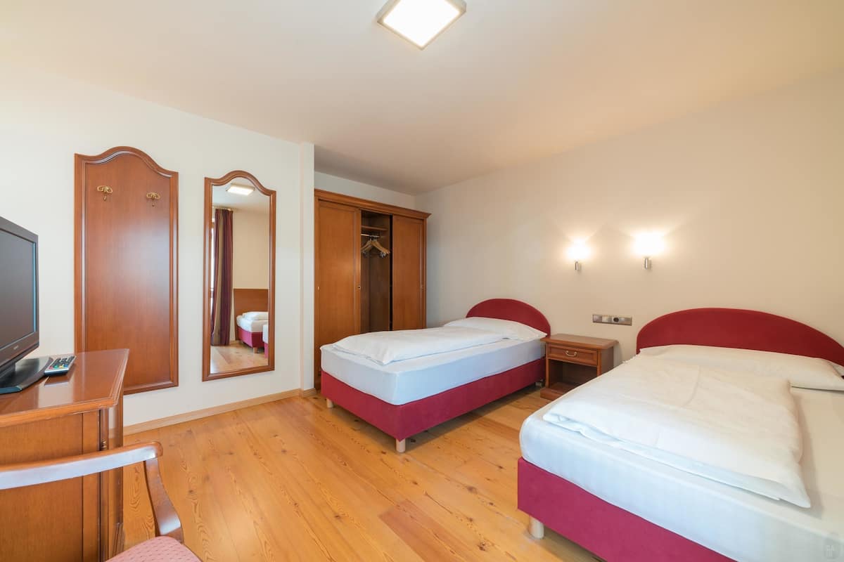 Een hotelkamer met twee bedden, een televisie, een bureau en een kledingkast.