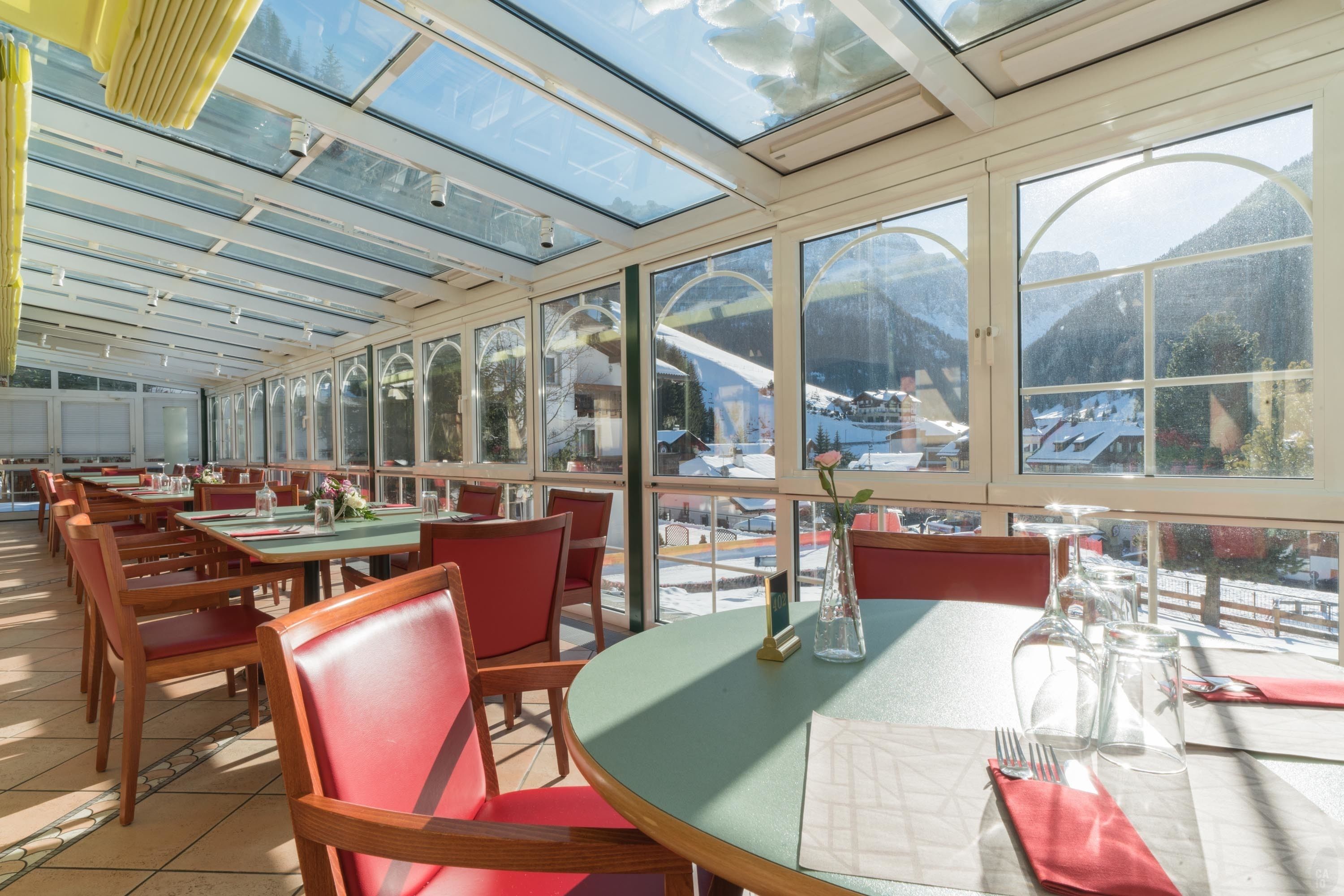 Un restaurant doté de grandes fenêtres, de chaises en bois et de tables dressées pour le service.