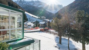 A snow-covered mountain village with a glass building, wooden houses, and a ski slope.