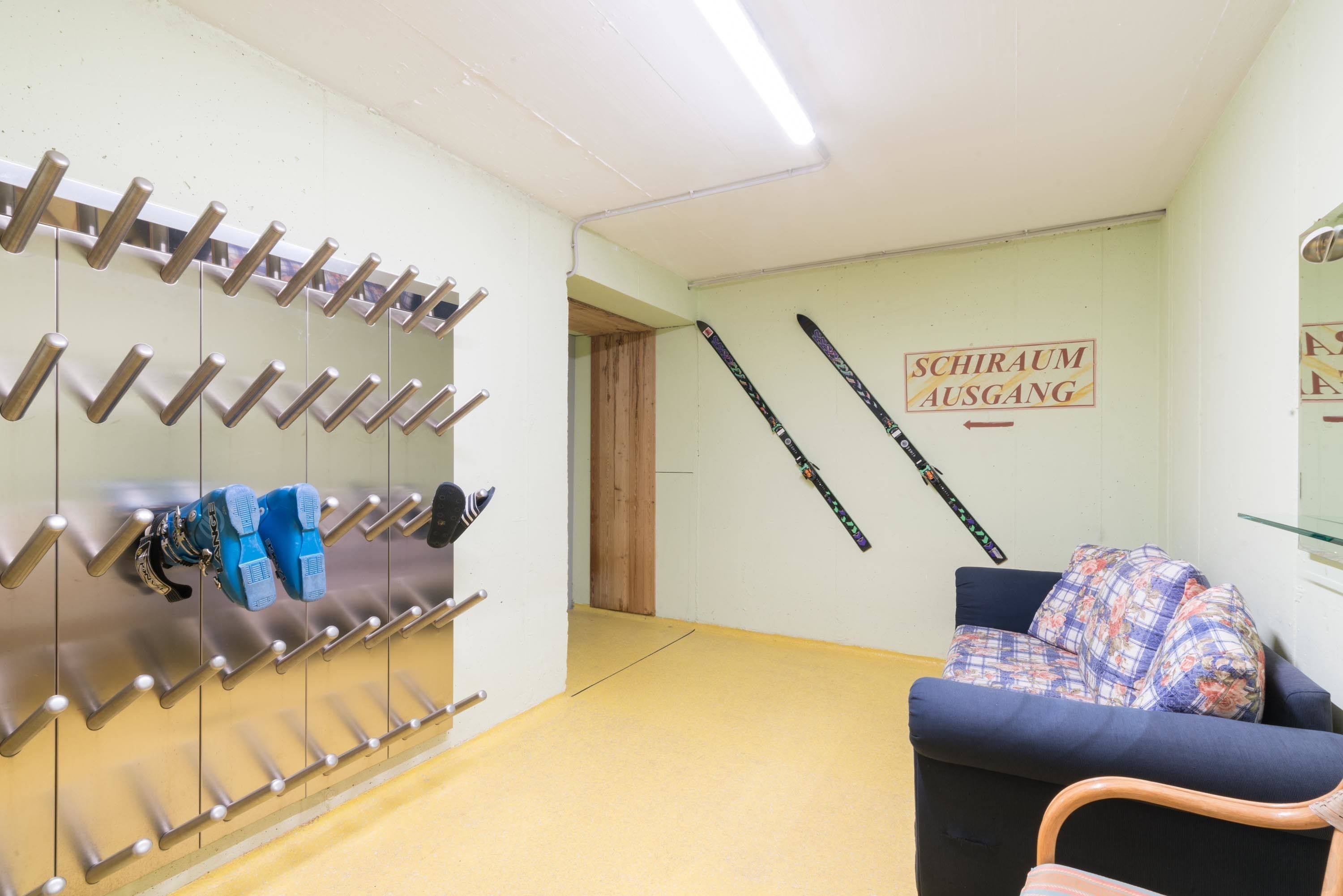 Ein Zimmer mit Skiregal, einer Couch und einem Schild, das einen Skiausstieg kennzeichnet.