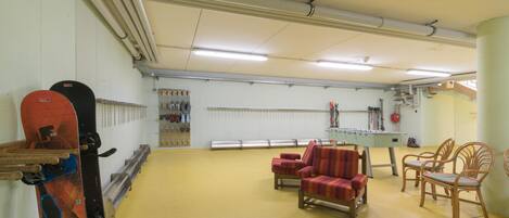 A spacious indoor area with a yellow floor, several chairs, and a foosball table.