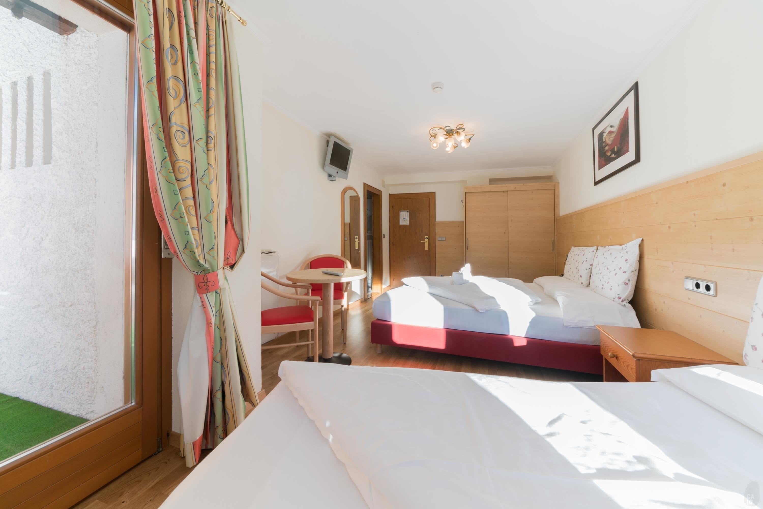 Habitación de hotel con cama, escritorio, silla, televisor y puerta.