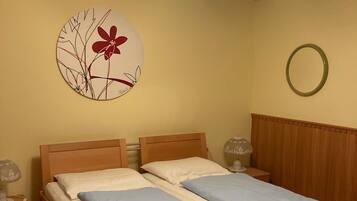 A double bed with a wooden headboard, a bedside table with a lamp, and a wall decoration.