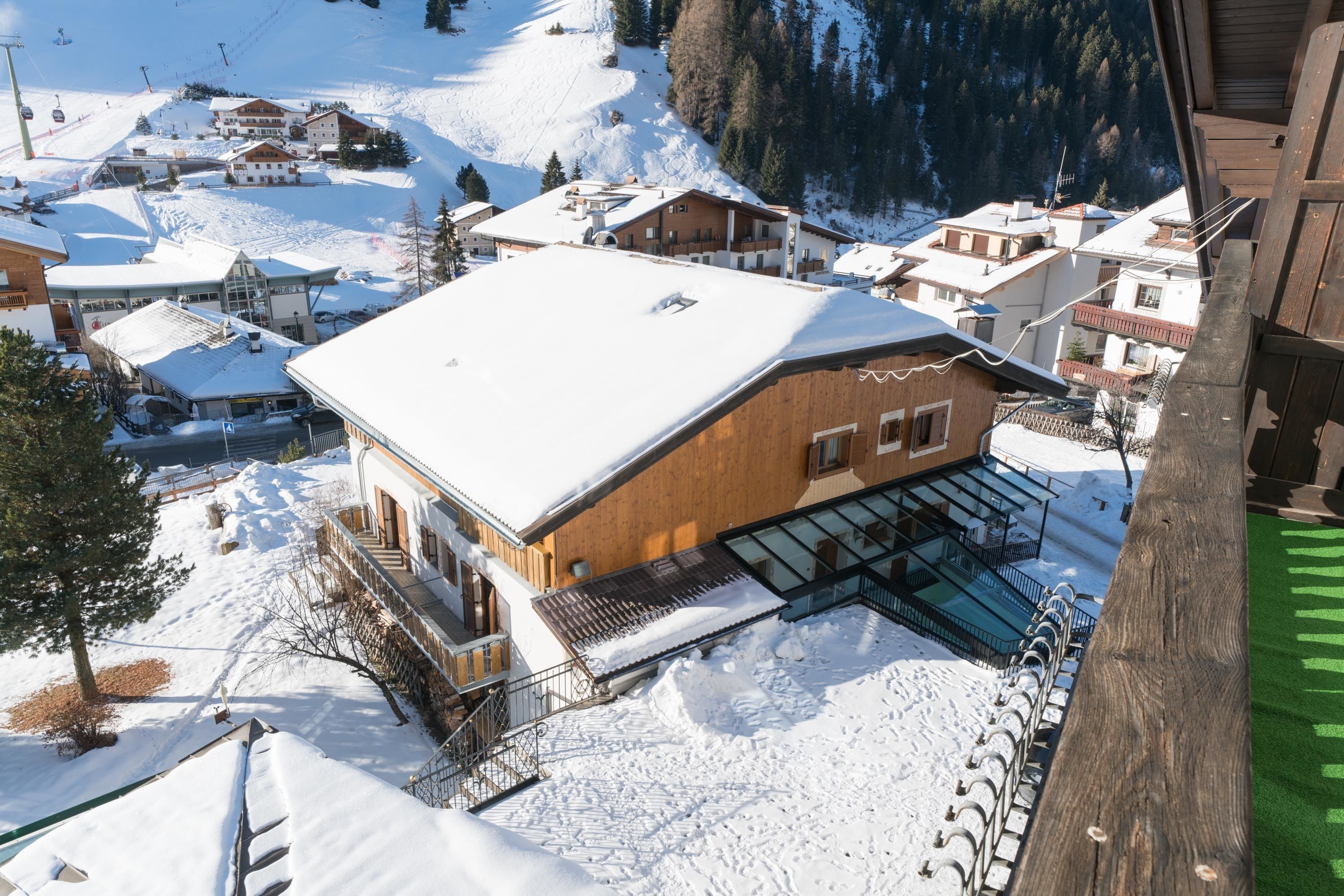 A wooden building with a snow-covered roof, a glass entrance, and a ski lift in the background.