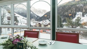 A restaurant with a table numbered 24, large windows offering a view of a snowy mountain landscape.