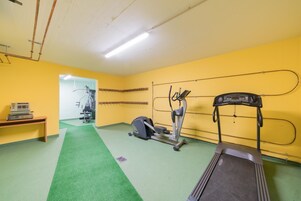 A gym with exercise equipment, a treadmill, and a green carpeted floor.