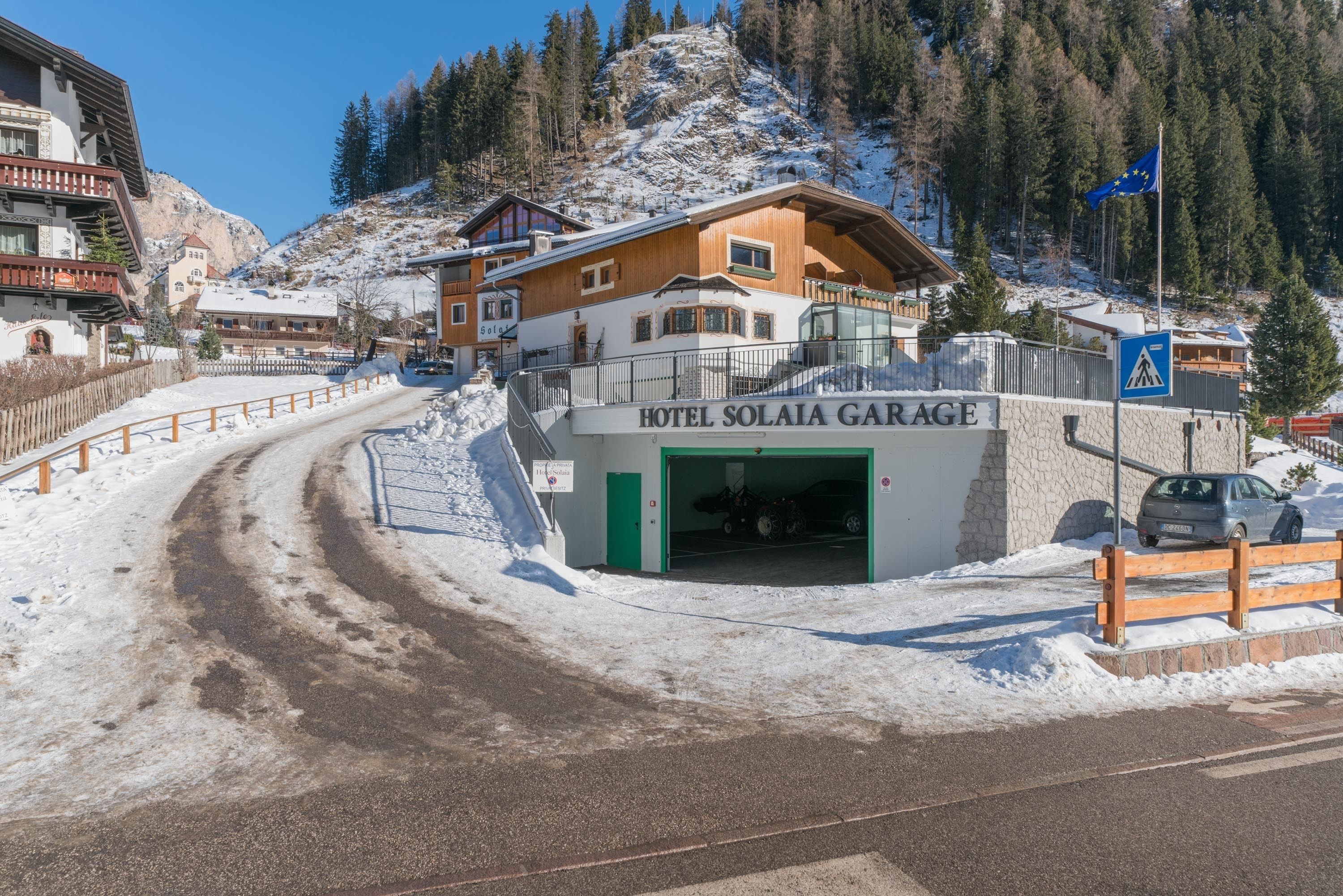 A hotel named 'Hotel Solalia Garage' with a wooden facade, a green entrance, and a parking area.