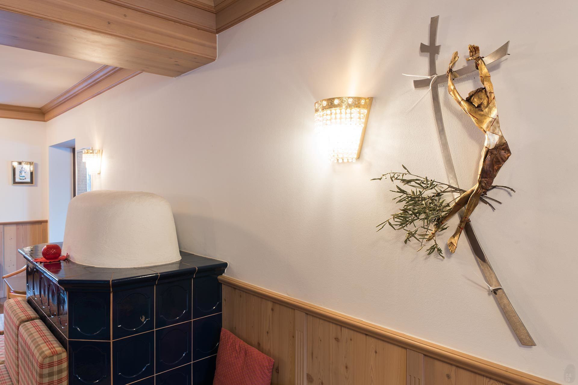 Une pièce avec un meuble bleu foncé, un coussin blanc et une sculpture en forme de croix fixée au mur.