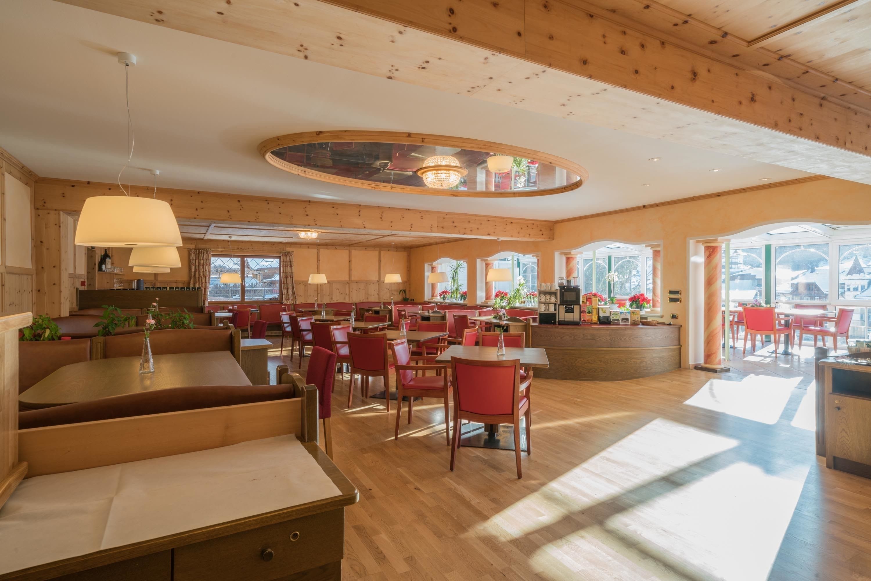 Un vaste espace dédié à la salle à manger, avec un lambris en bois, de nombreuses tables et chaises, et de grandes fenêtres qui laissent entrer la lumière naturelle.