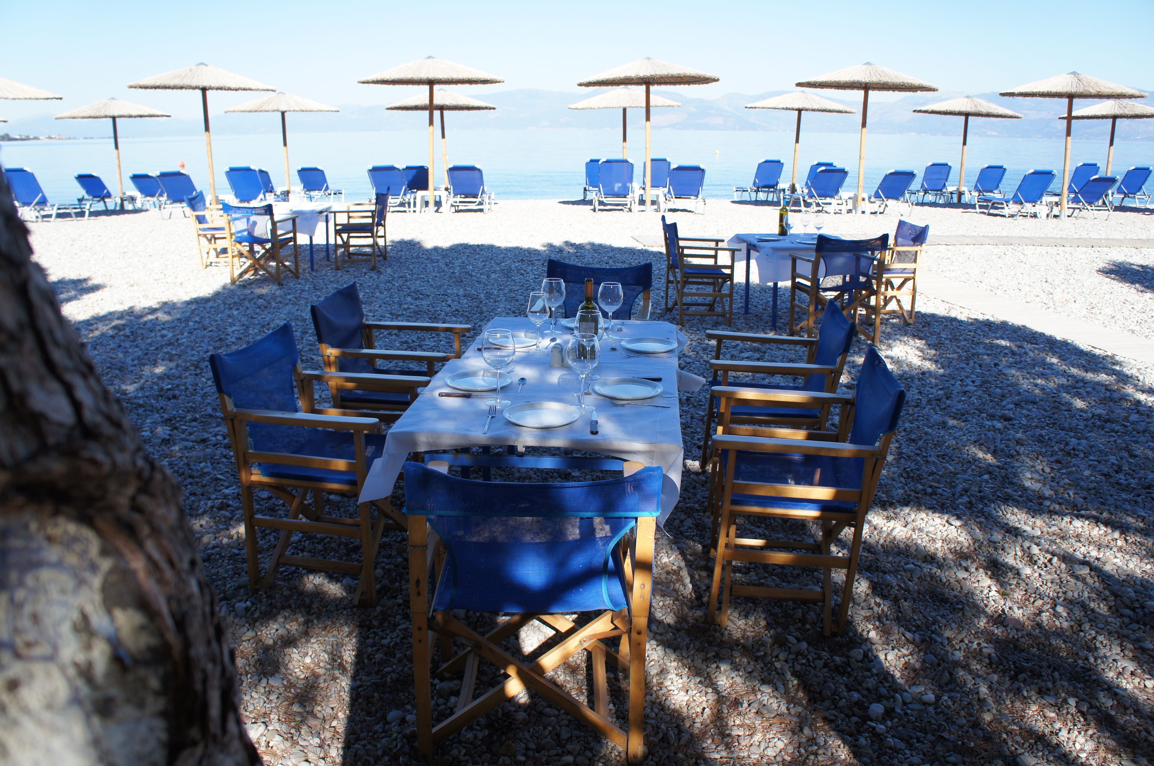 Montaje para comer frente al mar, con mesas, sillas, sombrillas y vistas al océano.