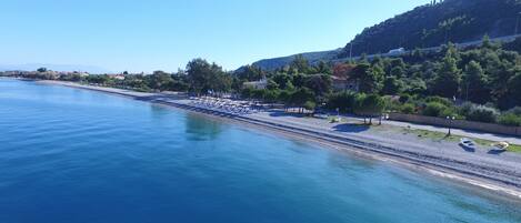 A coastal area with a beach, a road, and a hill in the background.