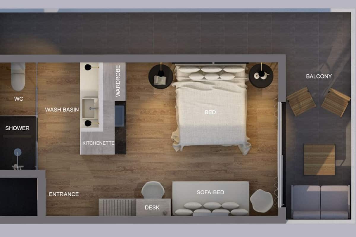 A floor plan of a hotel room with a bed, wardrobe, wash basin, shower, kitchenette, desk, sofa-bed, balcony, and entrance.