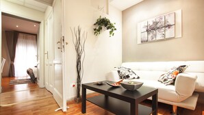 A modern living room with a white sofa, a black coffee table, and a painting on the wall. - B&B Cult Roma (Rome)