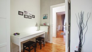A modern kitchen with a white countertop, two black stools, and a vase of flowers. - B&B Cult Roma (Rome)