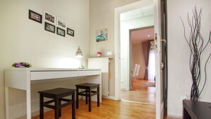A modern room with a white desk, two chairs, a lamp, and a vase with flowers. There are framed pictures on the wall and a door leading to another room. - B&B Cult Roma (Rome)