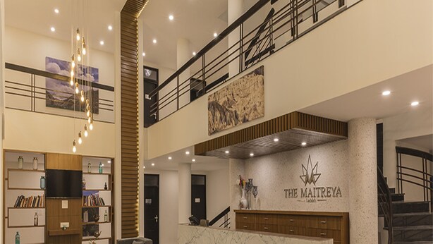 Un moderno vestíbulo de hotel con mostrador de recepción, zona de estar y una escalera.
