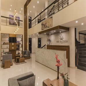 Un moderno vestíbulo de hotel con mostrador de recepción, zona de estar y una escalera.