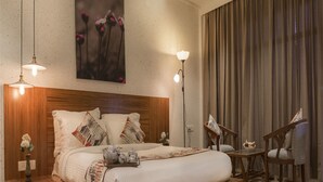 Un dormitorio moderno con una cama plataforma de madera, mesitas de noche con lámparas, un ventanal con cortinas y un cuadro en la pared.