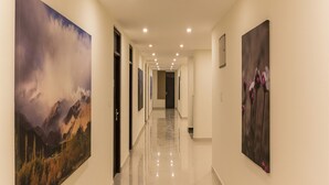 Un pasillo con piso pulido, obras de arte enmarcadas en las paredes e iluminación empotrada.