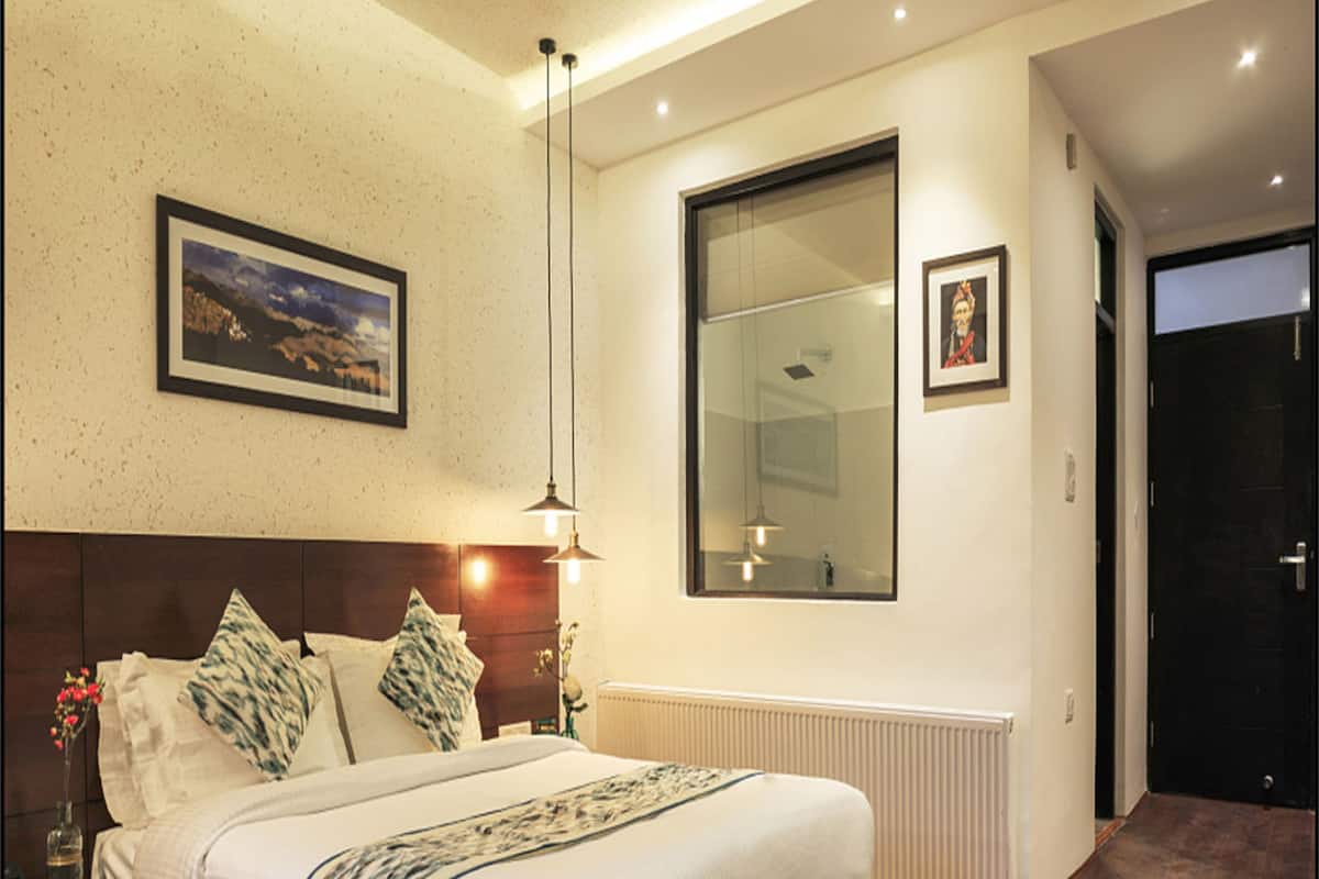 Un dormitorio moderno con una cama grande, una mesita de noche y una lámpara en ella, un amplio ventanal y una puerta.