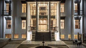 Una entrada de hotel moderna con una gran escalera que conduce al vestíbulo, con amplias ventanas de vidrio y una fachada bien iluminada.