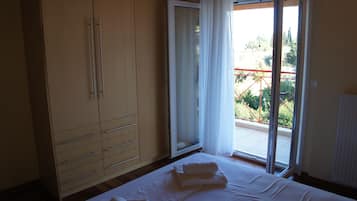 Un dormitorio con un armario grande, una cama con ropa de cama blanca y un ventanal corredero a un balcón.