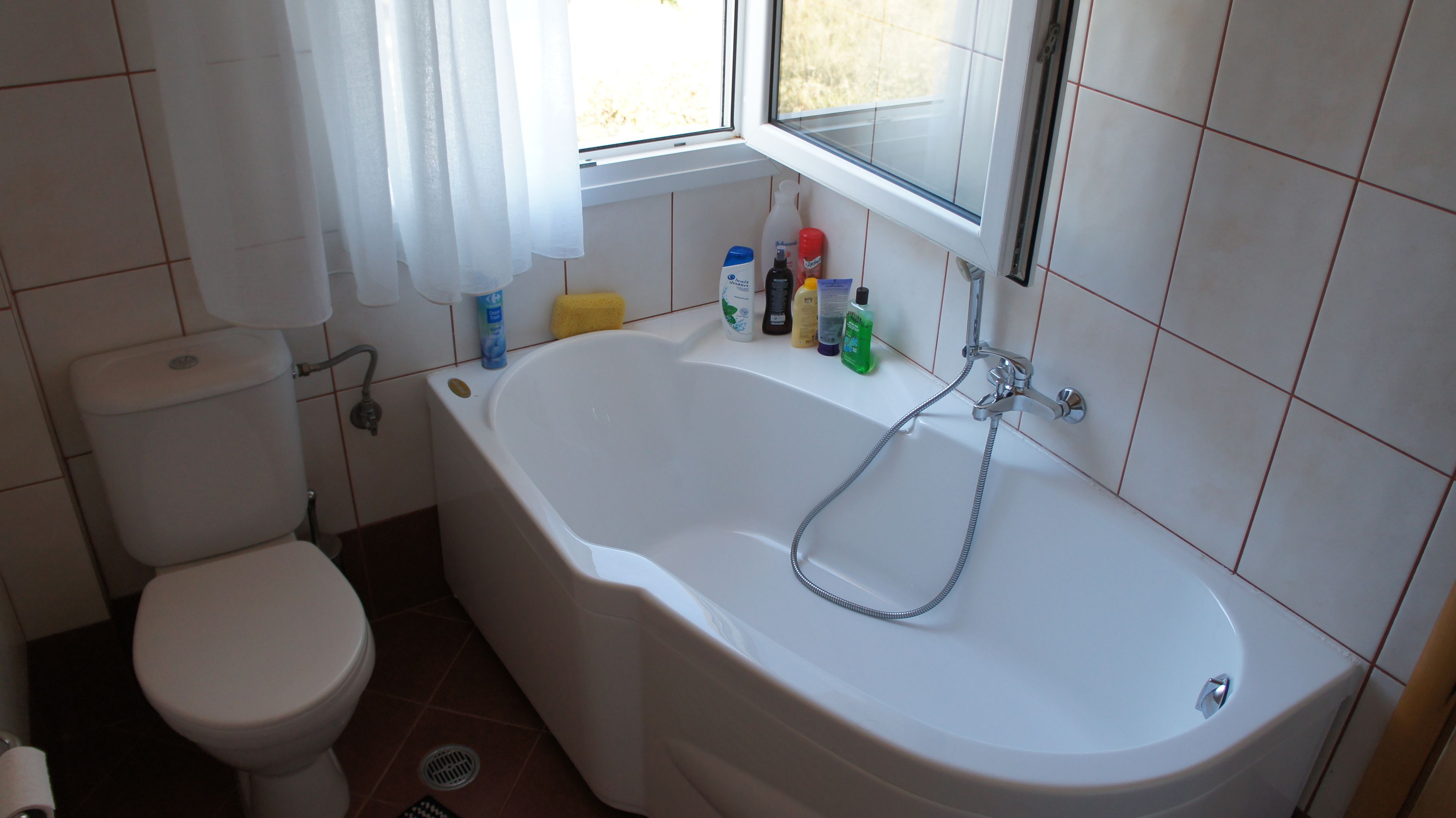 A bathroom with a bathtub, toilet, and window.
