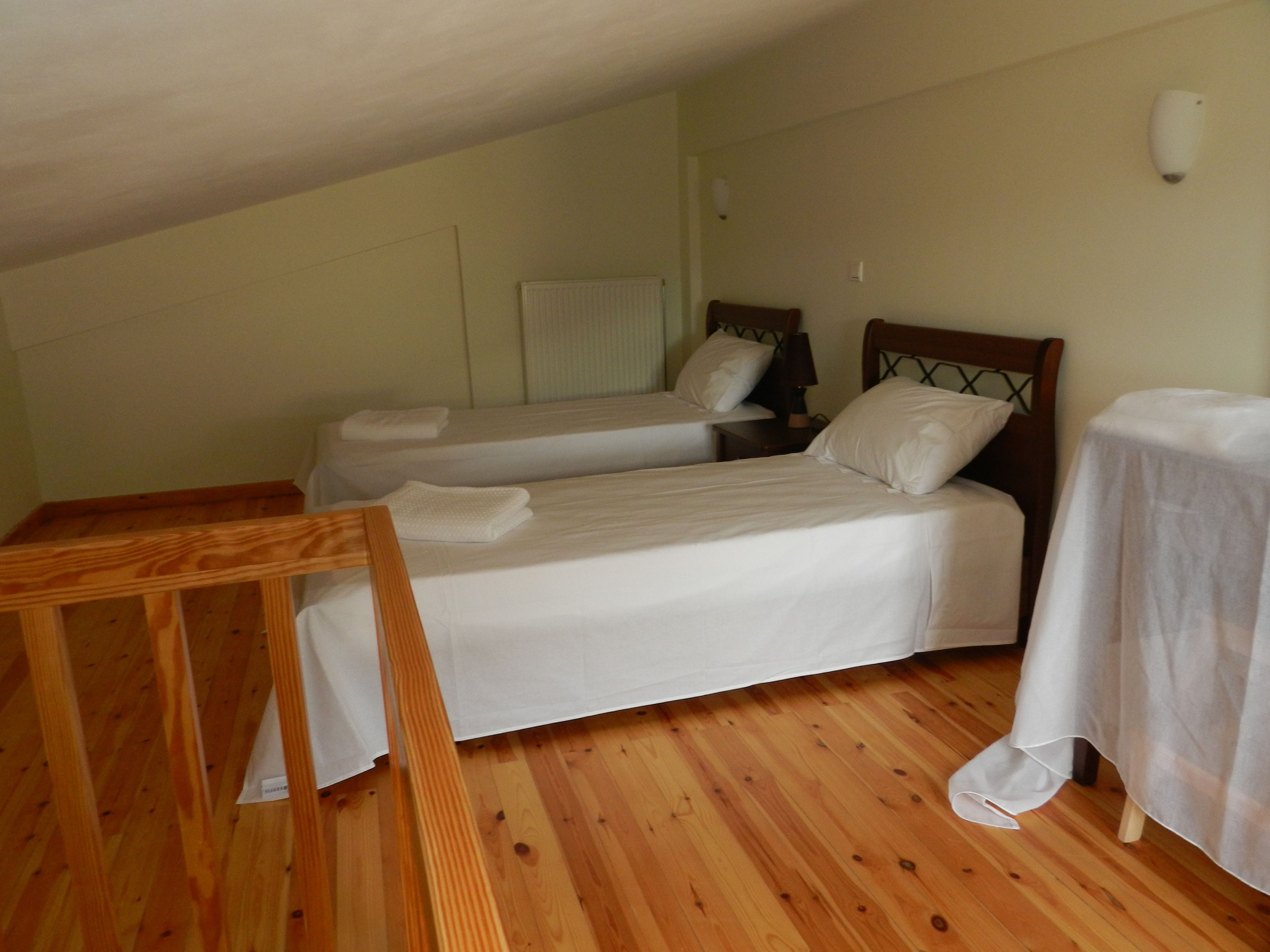 A room with two single beds, a wooden table, and a small table with a tablecloth.