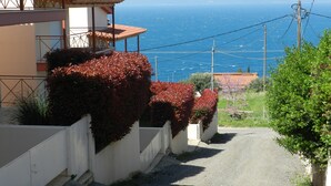 Una calle estrecha con un edificio a la izquierda y una vista al mar y las montañas en el fondo.