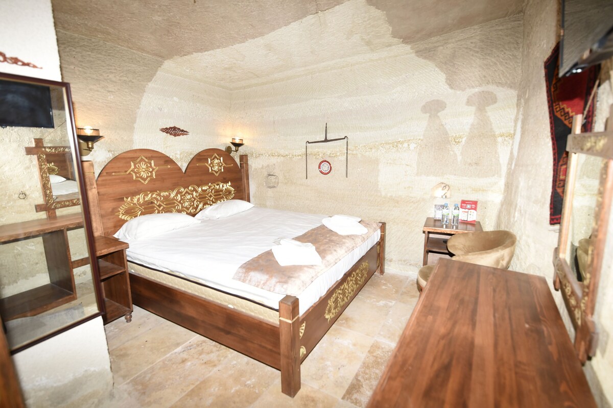 A bedroom with a wooden bed, a nightstand, a chair, and a small table.