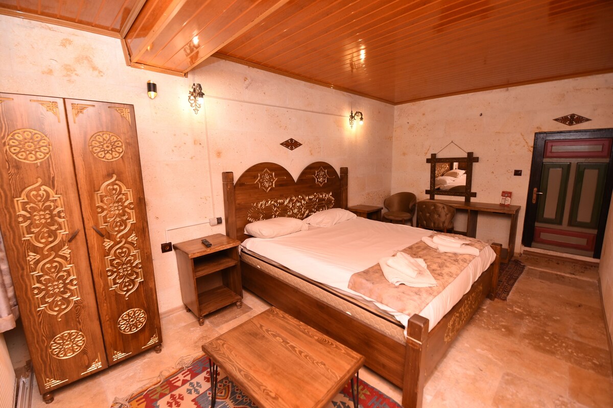 A wooden bed with a headboard, a nightstand, a wardrobe, and a small table.