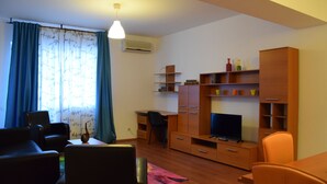 Un salon avec un téléviseur, des meubles en bois, un bureau et une chaise.