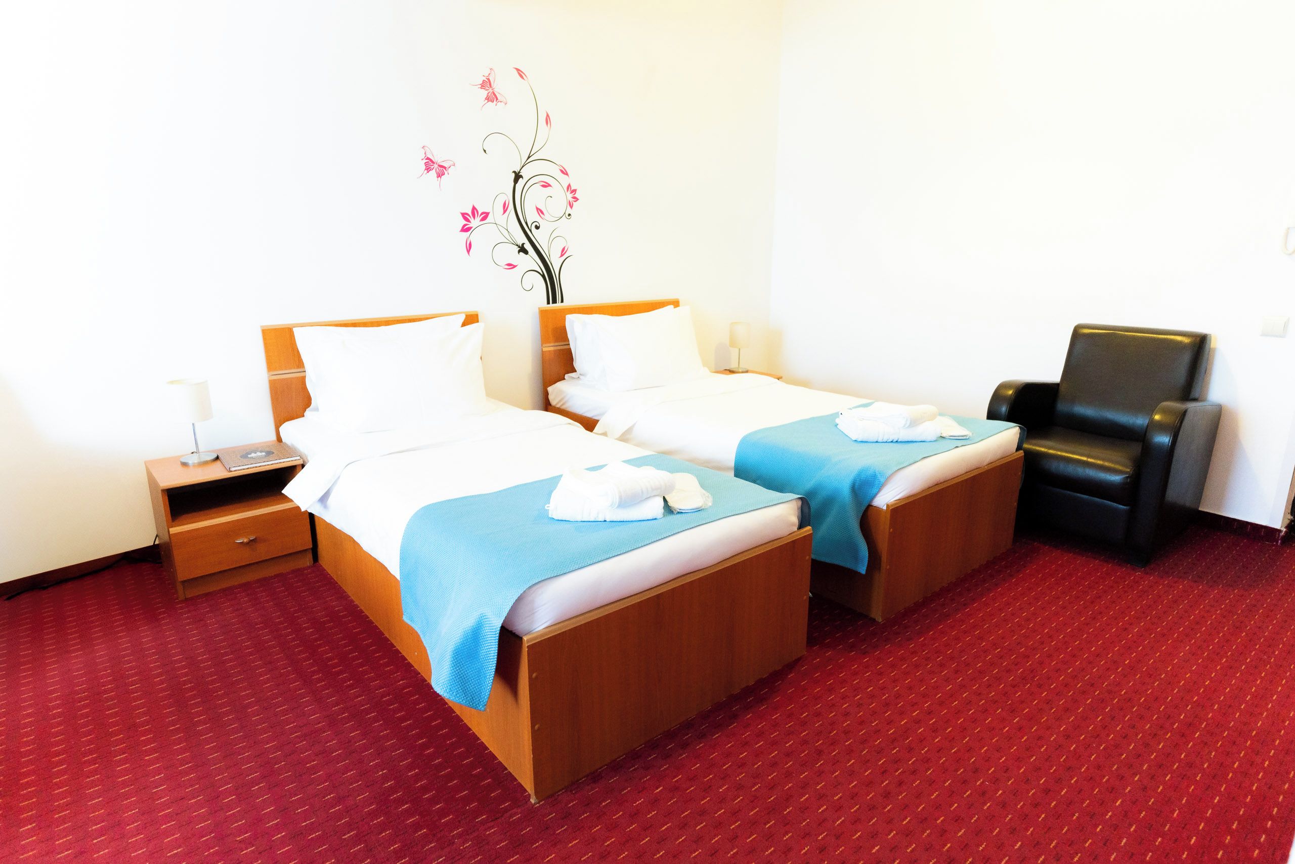Ein Hotelzimmer mit zwei Betten, einem Schreibtisch, einem Stuhl und einer Wanddekoration.