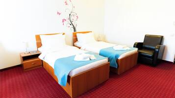 Ein Hotelzimmer mit zwei Betten, einem Schreibtisch, einem Stuhl und einer Wanddekoration.
