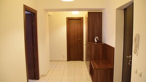 Un couloir avec une porte en bois, un banc et un téléphone fixé au mur.