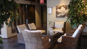 Un vestíbulo con muebles de mimbre, una mesa de centro de vidrio y una planta en maceta.